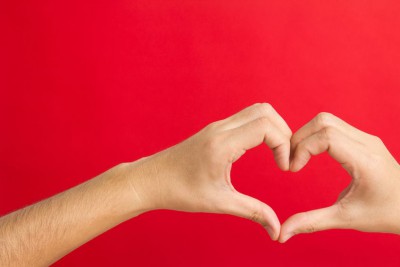 14120479 - hands in the shape of heart isolated on red background